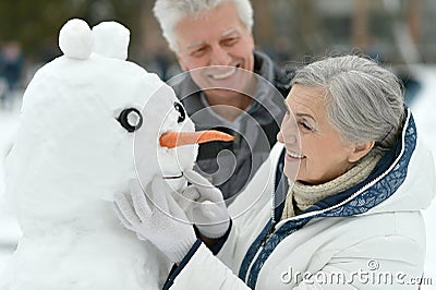 Happy senior couple with snowman Stock Photo