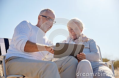 Happy senior couple with tablet pc on summer beach Stock Photo