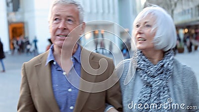 Happy Senior Couple Walking Through Outdoor Shopping Area stock video footage Happy Senior Couple Walking Through Outdoor Shopping Area stock video footage