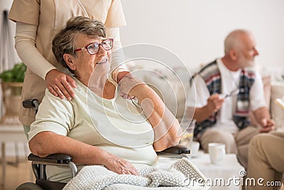 Happy senior lady sitting at wheelchair in nursing home for elderly Stock Photo