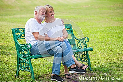 Happy senior loving couple relaxing at park embracing together in morning time. old people sitting on a bench in the autumn park Stock Photo