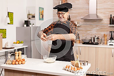 Happy senior man cracking eggs Stock Photo