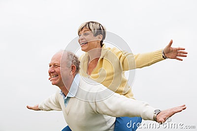 Happy senior man giving piggyback to woman Stock Photo