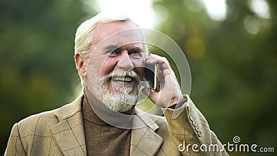 Happy senior man talking on phone in park, mobile communication, technology Stock Photo