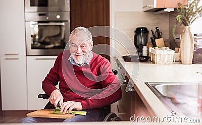 Senior man in wheelchair cooking in the kitchen. Stock Photo