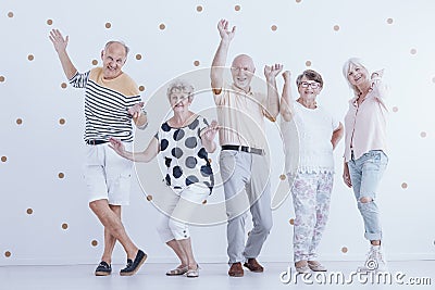 Happy senior people dancing against white background with gold d Stock Photo