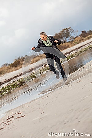 Happy senior woman frolicking on the beach Stock Photo