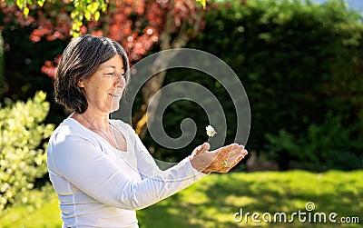 Happy senior woman releasing butterfly letting it fly Stock Photo