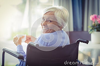 Happy senior woman on wheelchair holding a cup of tea Stock Photo