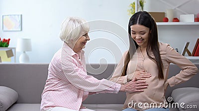 Happy senior woman holding pregnant granddaughters tummy, family replenishment Stock Photo