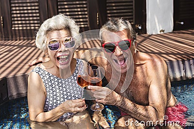 Happy seniors drinking prosecco in the pool Stock Photo