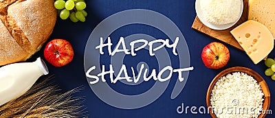 Happy Shavuot banner with dairy products, bread, fruits, wheat on blue background Stock Photo