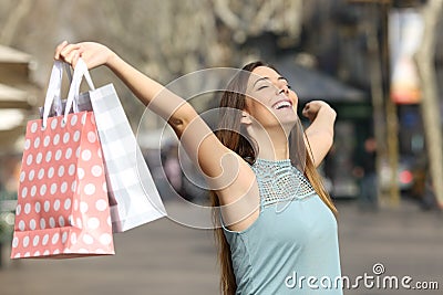 Happy shopper holding shopping bags in a street Stock Photo