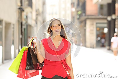 Happy shopper walking holding bags in the street Stock Photo