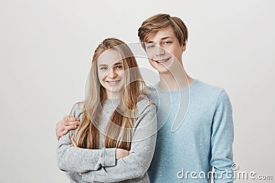 Happy siblings care for each other. Portrait of brother and sister with fair hair and braces, hugging and smiling Stock Photo