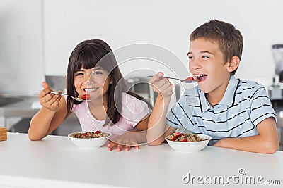 Happy siblings eating cereal for breakfast in kitchen Stock Photo