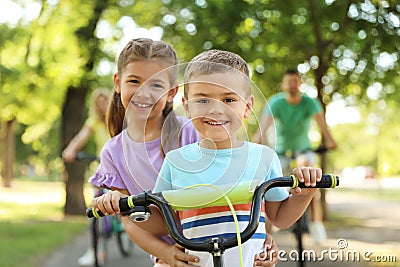 Happy siblings and parents riding bicycles in park Stock Photo