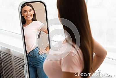 Happy Skinny Girl Looking At Reflection In Mirror At Home Stock Photo