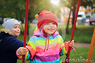 Happy Small children roll each other on swing. Children playing on the carousel. Children playground Stock Photo