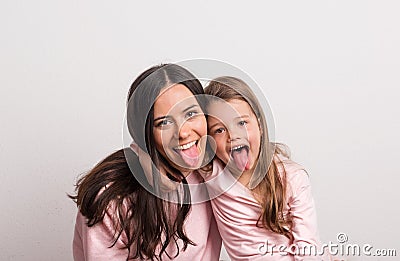 A small girl and her mother sticking tongues out in a studio. Stock Photo