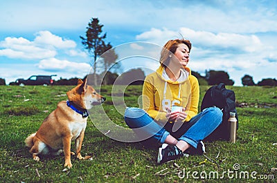 Happy smile girl holding in hands cup drink, red japanese dog shiba inu on green grass in outdoors nature park, beautiful young Stock Photo