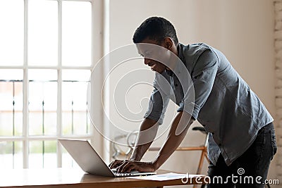 Happy smiling African American businessman using laptop in modern office Stock Photo