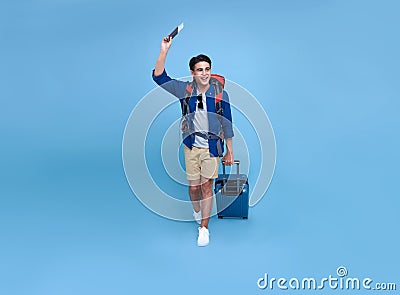 Happy smiling Asian bag packer man with passport and luggage enjoying their summer vacation getaway in blue background Stock Photo