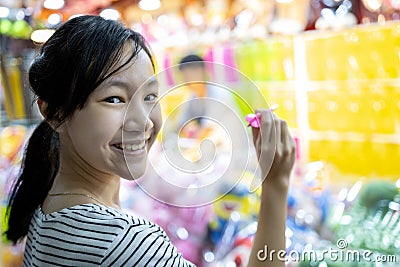 Happy smiling asian child girl holding a dart,looking at camera, having fun, female teen playing the dart game with balloons for Stock Photo