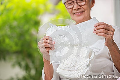 Happy smiling asian senior woman showing disposable diaper for adult,looking at nappy pamper with satisfaction,old elderly patient Stock Photo