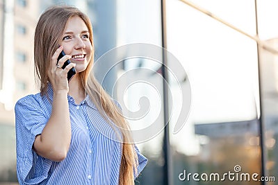 Happy smiling attractive woman talking on mobile phone near the office building Stock Photo