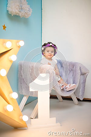 Happy smiling sweet baby girl sitting on armchair with shining light star, Birthday girl, One year old Stock Photo