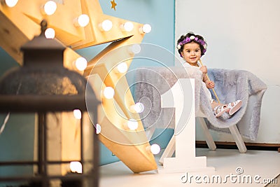 Happy smiling sweet baby girl sitting on armchair with shining light star, Birthday girl, One year old Stock Photo