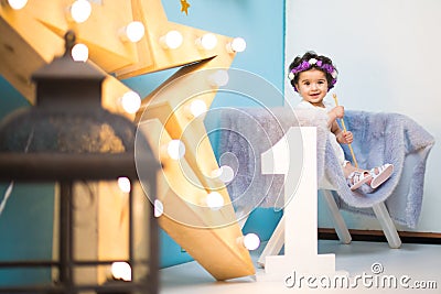 Happy smiling sweet baby girl sitting on armchair with shining light star, Birthday girl, One year old Stock Photo