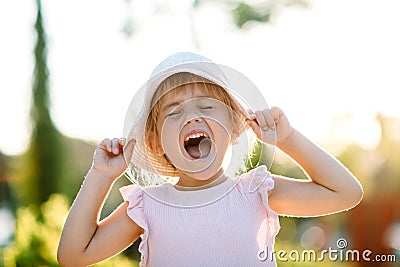 Happy and smiling blonde toddler girl in pink dress and hat. Happiness. Outdoor. Summer, sunset light Stock Photo