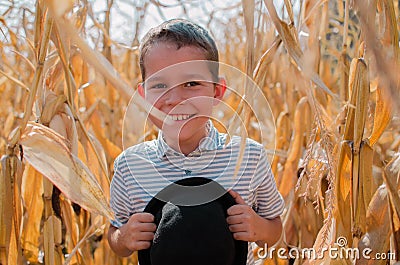 Happy smiling boy. Cute young 10 year old boy with black hat in his hands. Child in hte corn field - harvest season Stock Photo