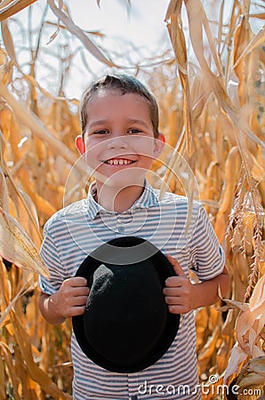 Happy smiling boy. Cute young 10 year old boy with black hat in his hands. Child in hte corn field - harvest season Stock Photo