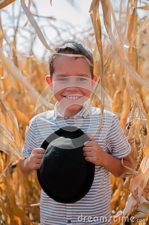 Happy smiling boy. Cute young 10 year old boy with black hat in his hands. Child in hte corn field - harvest season Stock Photo