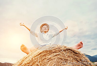 Happy smiling boy sits astride on the haystack Stock Photo