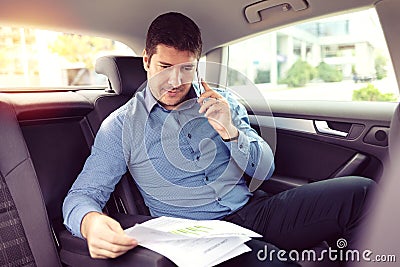 Happy smiling business man talking on phone doing business while siting in a taxi Stock Photo