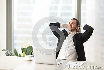 Happy smiling businessman relaxing at work desk in modern office Stock Photo