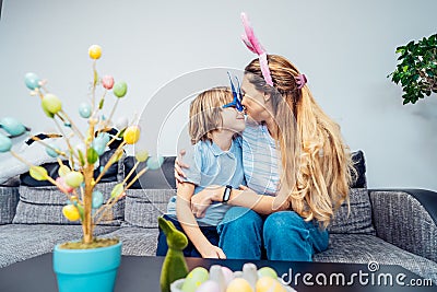 Happy smiling Caucasian mother and her son in bunny ears having fun at home on Easter day. Family sitting on sofa at Stock Photo