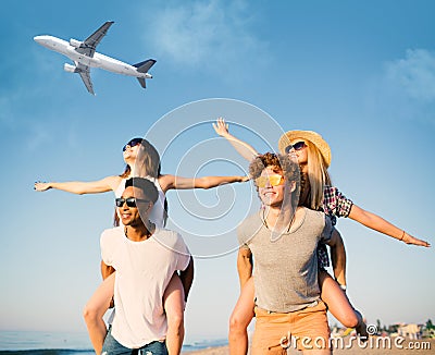 Happy smiling couples playing at the beach with aircraft in the sky Stock Photo