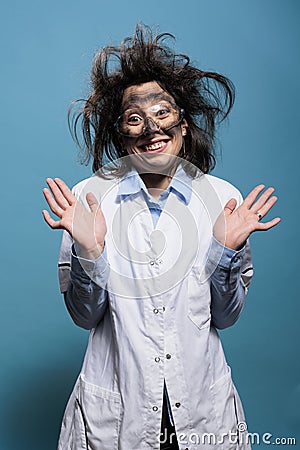 Happy smiling crazy scientist with messy hairstyle and dirty face acting innocent after dangerous explosion Stock Photo