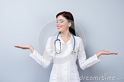 Happy smiling doctor asking to make a choice between two objects. Pretty handsome lady holding showing two profucts objects. Beaut Stock Photo