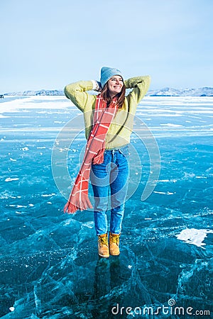 Happy smiling female traveler enjoying good day while standing on frozen Baikal lake Stock Photo