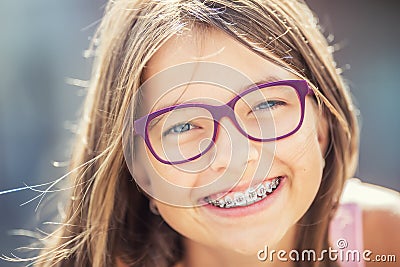 Happy smiling girl with dental braces and glasses. Young cute caucasian blond girl wearing teeth braces and glasses Stock Photo