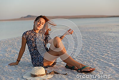 Happy smiling girl enjoying the sunset, closed her eyes to pleasure, sit on salt Stock Photo