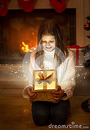 Happy smiling girl opening shiny Christmas gift box. Light and s Stock Photo