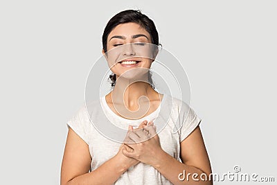 Smiling indian millennial girl standing with folded hands near heart. Stock Photo
