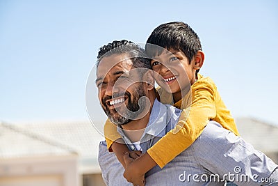 Happy smiling indian father giving son ride on back Stock Photo